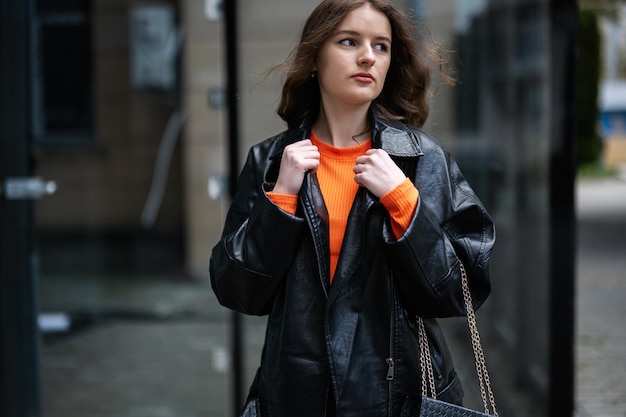 Portret van een jonge dame in leren jas en oranje mock coltrui