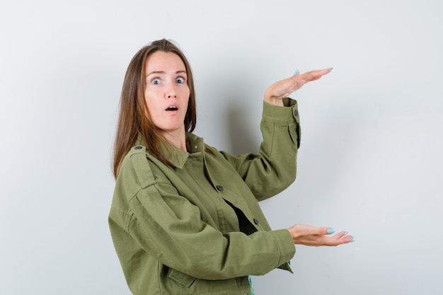 Portret van een jonge dame met een groot bord in een groen jasje en een geschokt vooraanzicht