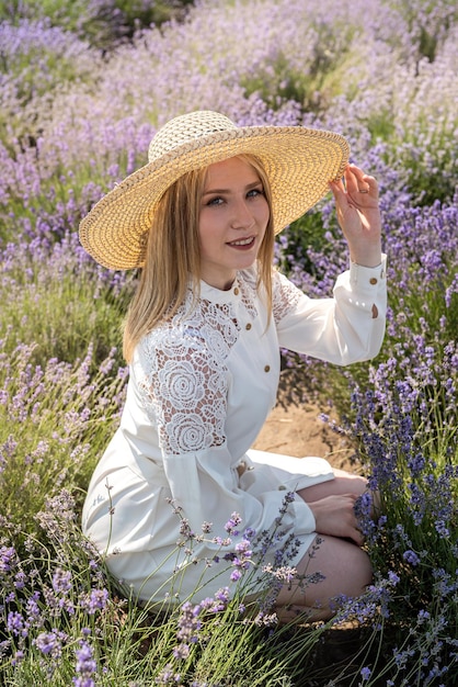 Portret van een jonge dame met hoed zittend op lavendelveld