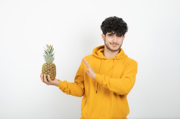 Portret van een jonge donkerbruine mens die en ananas bevindt zich houdt.