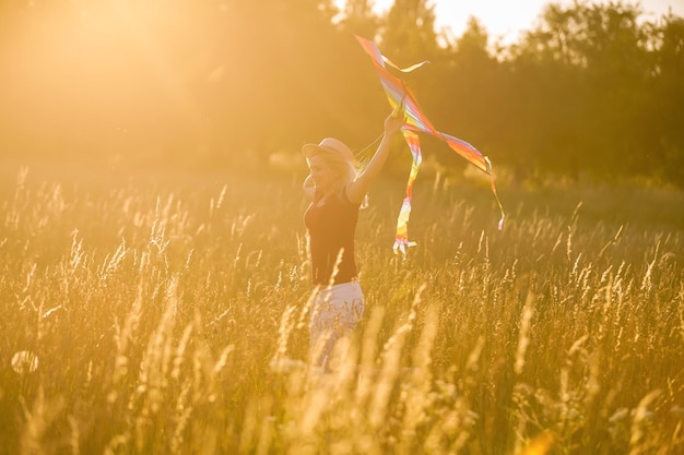 Foto portret van een jonge en zorgeloze vrouw die vlieger lanceert op de greenfield. concept van actieve levensstijl in de natuur