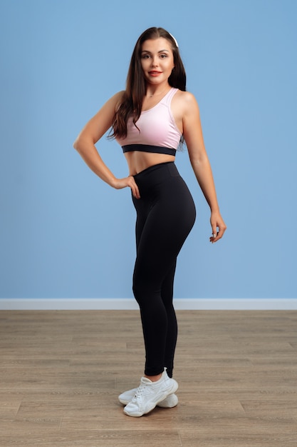 Portret van een jonge fitness vrouw in sportkleding het stellen in studio