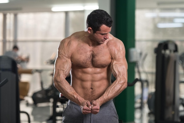 Portret van een jonge fysiek fit harige man toont zijn goed getrainde lichaam gespierde atletische bodybuilder Fitness Model poseren na oefeningen