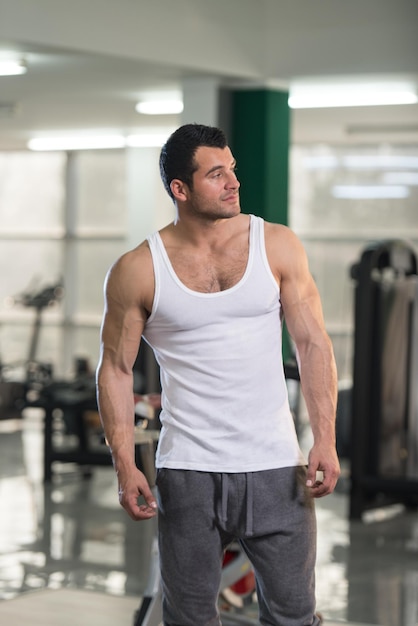 Portret van een jonge fysiek fit Man In wit hemd toont zijn goed opgeleide lichaam gespierde atletische Bodybuilder Fitness Model poseren na oefeningen