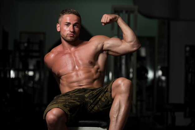 Portret van een jonge fysiek fit man toont zijn goed opgeleide lichaam gespierde atletische bodybuilder Fitness Model poseren na oefeningen