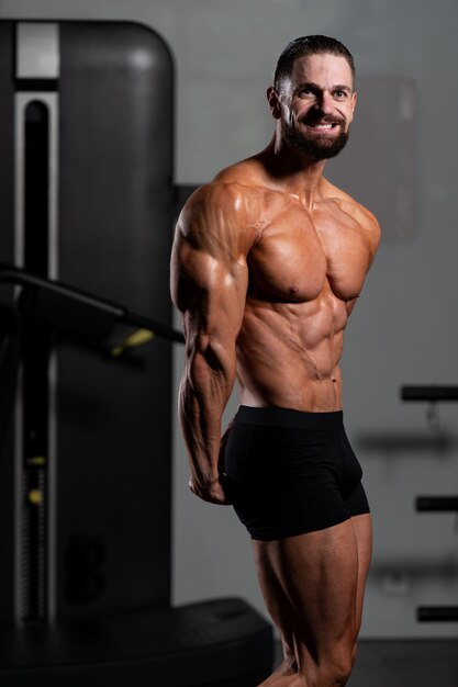 Portret van een jonge fysiek fit Man toont zijn goed opgeleide lichaam gespierde atletische Bodybuilder Fitness Model poseren na oefeningen