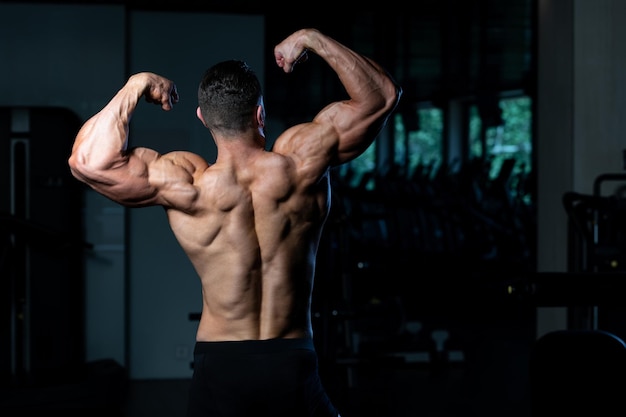 Portret van een jonge fysiek fit Man toont zijn goed opgeleide lichaam gespierde atletische Bodybuilder Fitness Model poseren na oefeningen