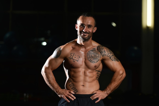 Portret van een jonge fysiek Fit Tattoo Man toont zijn goed opgeleide lichaam gespierde atletische Bodybuilder Fitness Model poseren na oefeningen