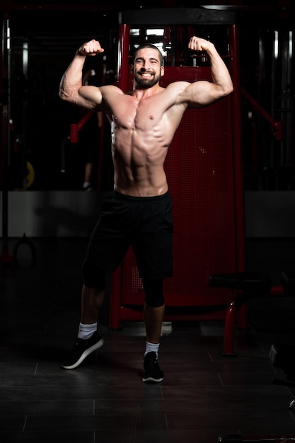 Portret van een jonge fysiek fitte man die zijn goed getrainde lichaam toont - gespierde atletische bodybuilder Fitness Model poseren na oefeningen