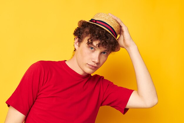 Portret van een jonge gekrulde man emoties rode tshirt hoed studio gele achtergrond ongewijzigd