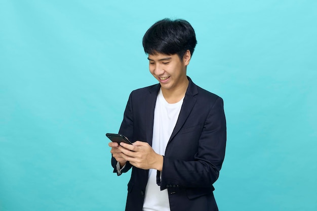 Portret van een jonge glimlachende knappe aziatische man in een semi-formeel pak met een mobiele telefoon