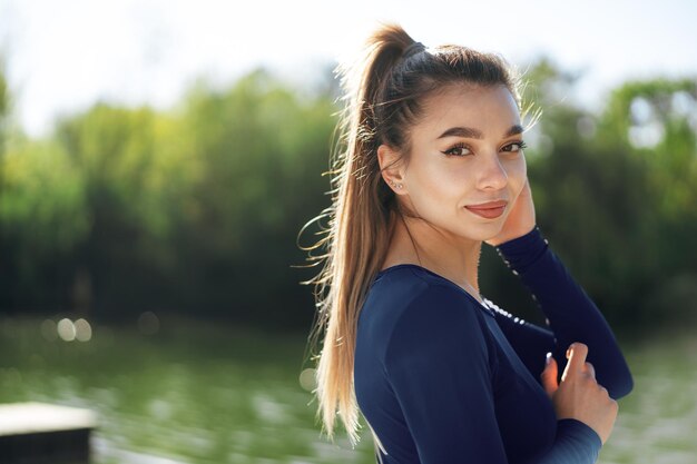 Portret van een jonge glimlachende vrouw die sportkleding draagt in het ochtendpark