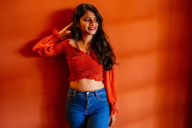 Portret van een jonge Indiase vrouw in casual stijl jeans en blouse oranje muren city