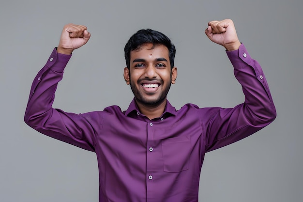 Foto portret van een jonge indiase zakenman die succes viert op een grijze achtergrond