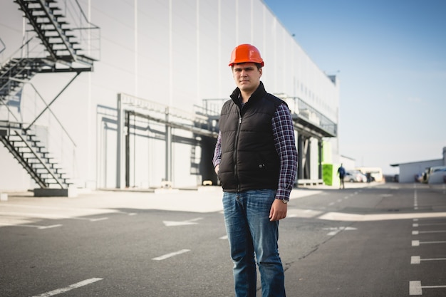 Portret van een jonge ingenieur in een helm die zich voordeed in het magazijn