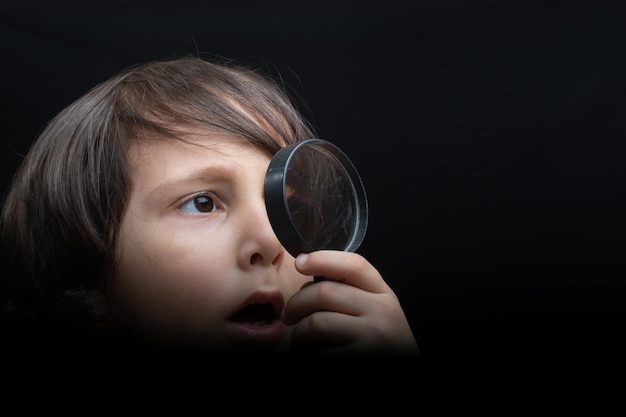 Portret van een jonge jongen die door het vergrootglas kijkt