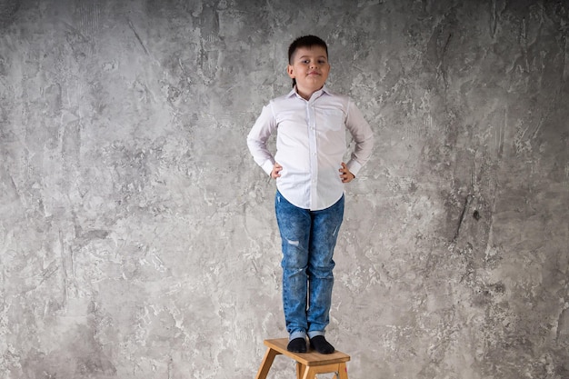 Portret van een jonge jongen die op een stoel staat geïsoleerd op een witte achtergrond in de studio