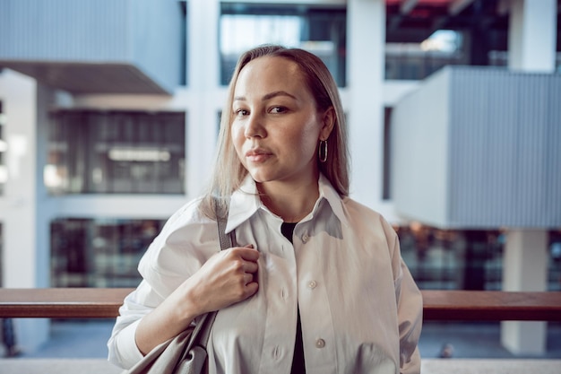 Portret van een jonge kantoorvrouw die op het balkon staat en geniet van het uitzicht op de stad