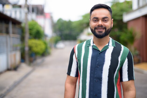 Portret van een jonge knappe bebaarde Indiase man in de straten buiten