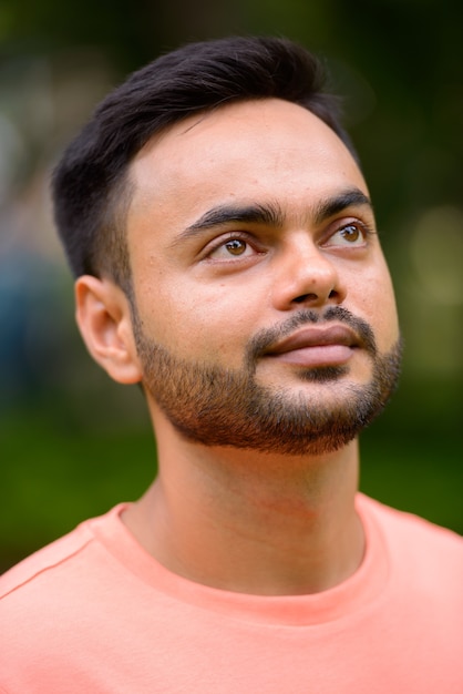 Portret van een jonge knappe bebaarde Indiase man in het park buitenshuis