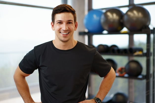 Portret van een jonge knappe fitnesstrainer in een sportschool