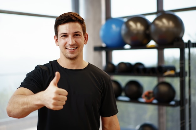 Portret van een jonge knappe fitnesstrainer in een sportschool