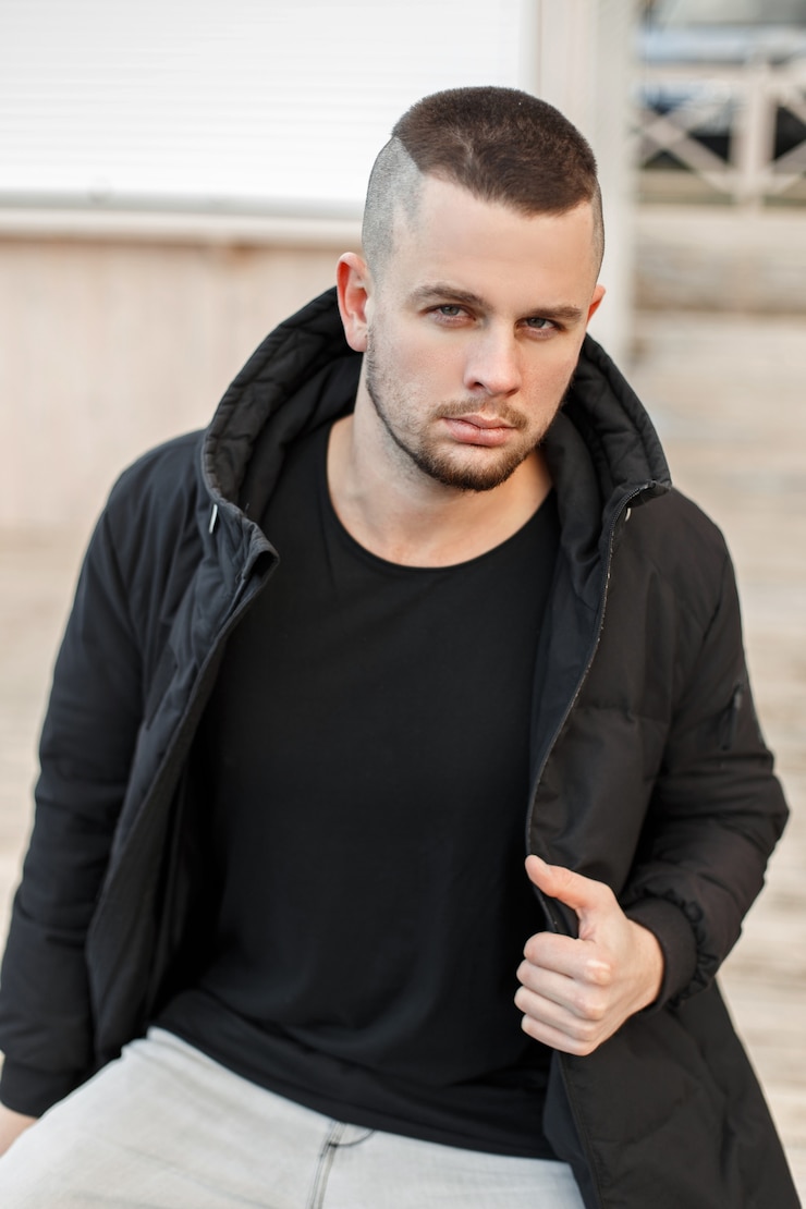 Foto portret van een jonge knappe jongen in een zwarte winterjas op straat