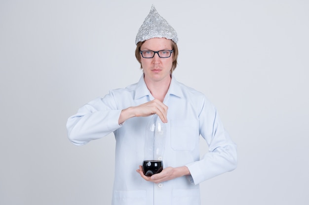 Portret van een jonge knappe man arts die aluminiumfolie hoed draagt als concept van de complottheorie op wit