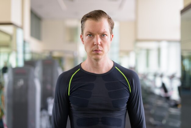 Foto portret van een jonge knappe man die op de sportschool denkt tijdens covid-19