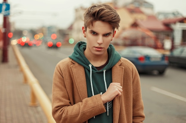 Portret van een jonge knappe man in een trendy stijlvolle jas op straat