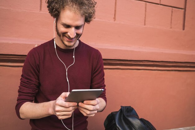 Portret van een jonge knappe man met zijn digitale tablet buiten in de straat. Technologie en stedelijk concept.