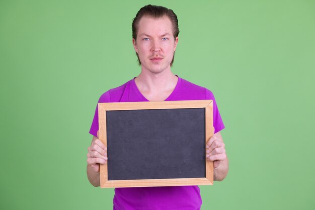 Portret van een jonge knappe Scandinavische man met paars shirt tegen Chromakey of groene muur