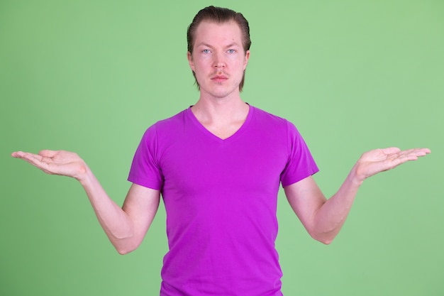 Portret van een jonge knappe Scandinavische man met paars shirt tegen Chromakey of groene muur