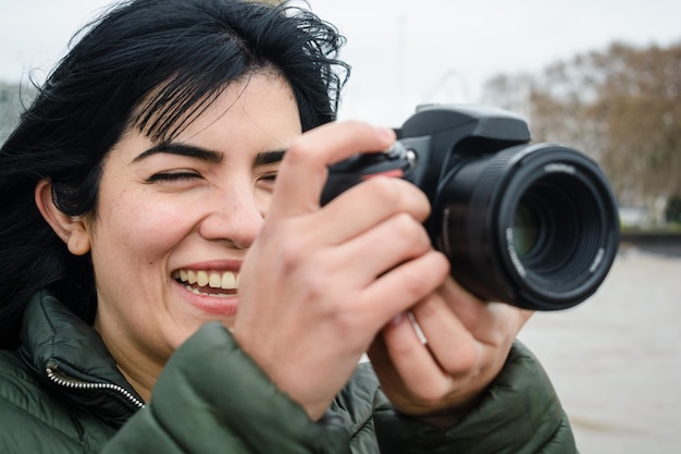 portret van een jonge Latijnse vrouw die glimlacht en een foto maakt met haar digitale DSLR-camera