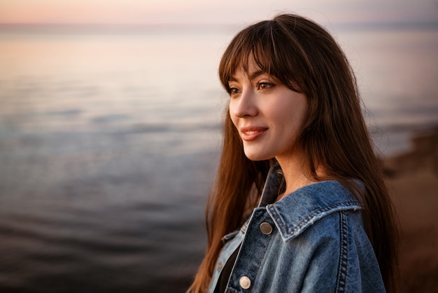 Portret van een jonge leuke vrouw op de achtergrond van de zee bij zonsondergang