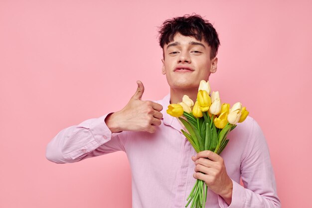 Portret van een jonge man boeket van gele bloemen romantiek poseren mode roze achtergrond ongewijzigd