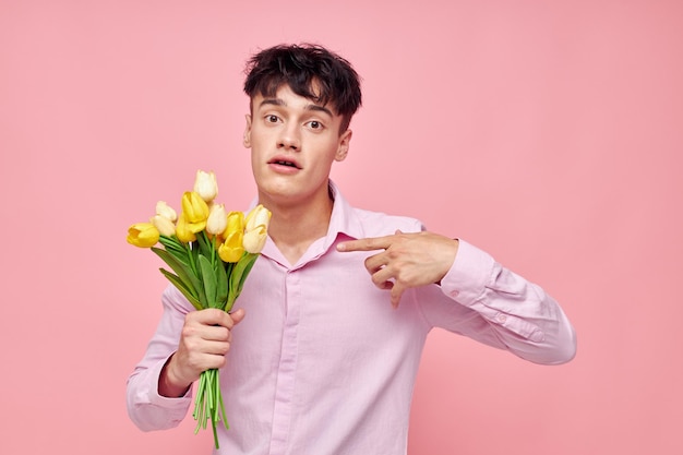 Portret van een jonge man boeket van gele bloemen romantiek poseren mode roze achtergrond ongewijzigd