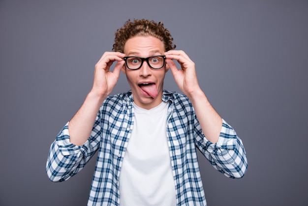 Portret van een jonge man casual shirt aanraken van glazen grimassen weergegeven: tong uit