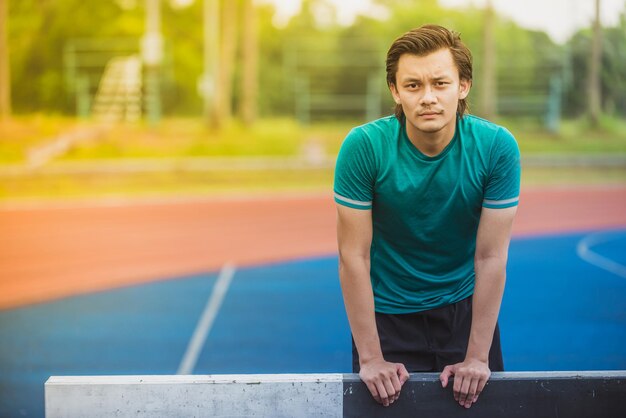 Foto portret van een jonge man die achter een hindernis op de loopbaan staat