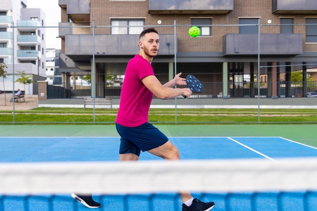 Portret van een jonge man die backhand pickleball raakt tijdens een wedstrijd