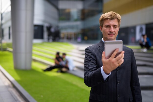 Foto portret van een jonge man die buiten een mobiele telefoon gebruikt