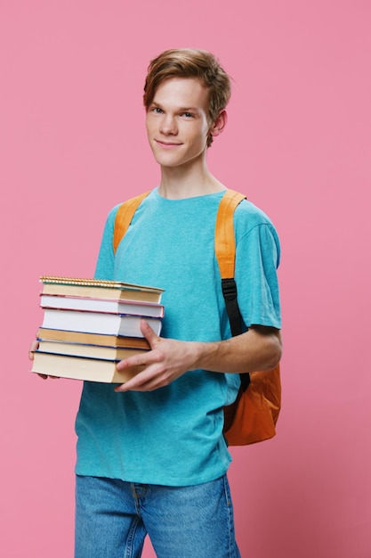 Portret van een jonge man die een boek vasthoudt terwijl hij tegen een roze achtergrond staat