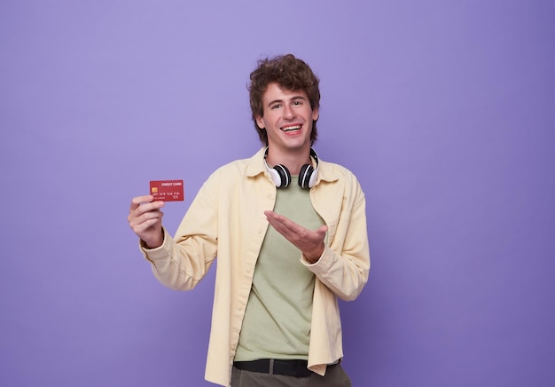 Portret van een jonge man die een creditcard in de hand presenteert en vertrouwen en vertrouwen toont voor het betalen