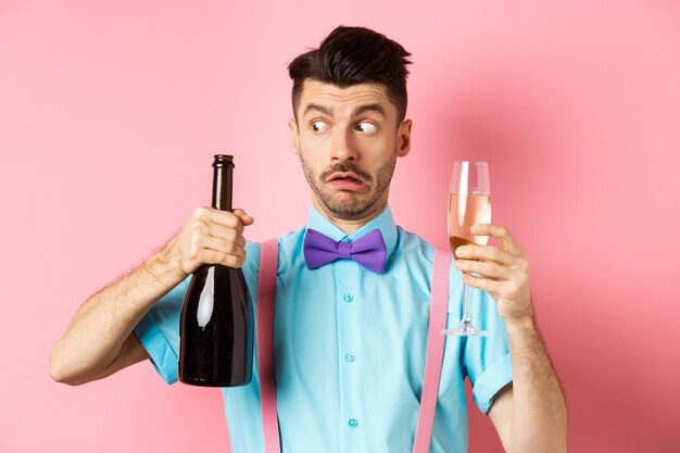 Foto portret van een jonge man die een glas drinkt op een roze achtergrond