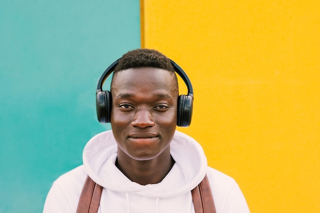 Portret van een jonge man die een mobiele telefoon tegen de muur gebruikt