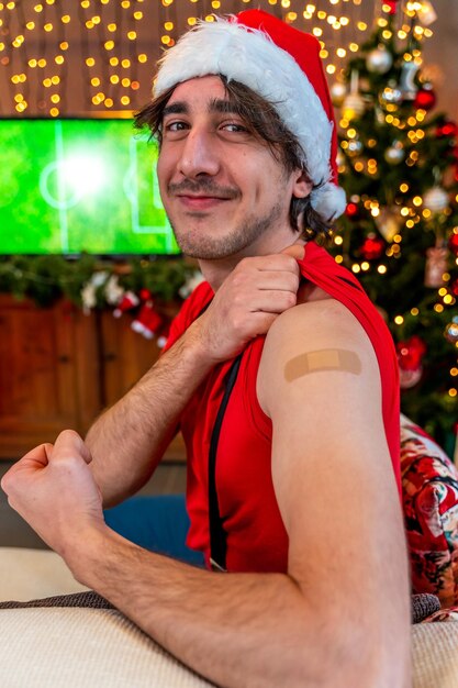 Foto portret van een jonge man die glimlacht na een vaccinatie - een man die haar arm met verband laat zien