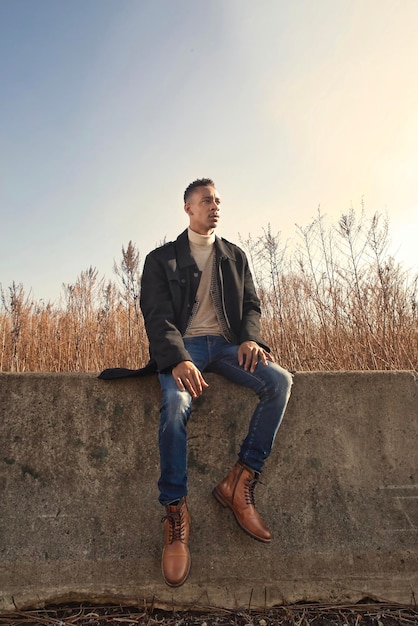 Portret van een jonge man die op een reling staat tegen een heldere lucht
