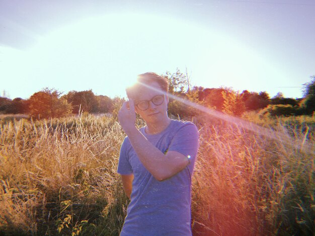 Foto portret van een jonge man die op een zonnige dag op het veld staat