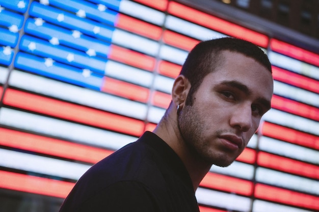 Foto portret van een jonge man die tegen de amerikaanse vlag staat