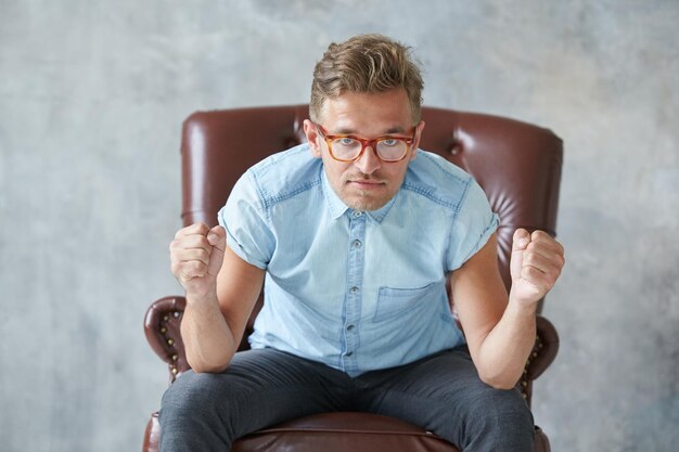 Foto portret van een jonge man die tegen de muur zit